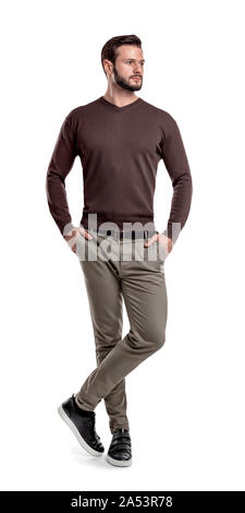 Ein Mann in den Hosen, Pullover und Turnschuhe steht mit einem Bein über einen anderen und suchen seitwärts. Stockfoto