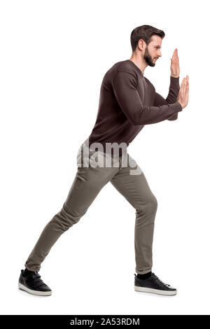 Ein bärtiger Mann, der bereit im Casual Hosen pressen seine Hände über ein unsichtbares Objekt, um es zu bewegen. Stockfoto