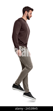 Eine ernsthafte, bärtigen Mann in legere Kleidung steht in der Seitenansicht, als wenn am Hang. Stockfoto
