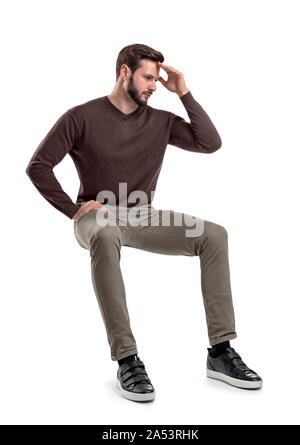 Eine isolierte bärtigen Mann in Freizeitkleidung sitzt auf einem weißen Hintergrund mit einer Hand seine Stirn zu berühren. Stockfoto