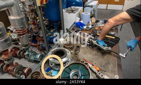 Maschinenbauer in Latex Handschuhe Lager aus der einen Anker auf seiner Werkbank in einem Pumpenraum Stockfoto