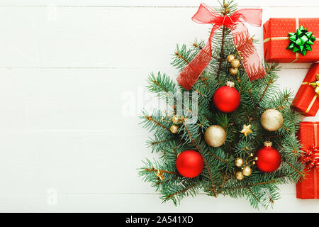 Weihnachten Neujahr Muster Zusammensetzung: Weihnachtsbaum aus Tannenzweigen, rot Geschenkboxen auf weißem Holz- Hintergrund, Konzept von Urlaub Feier Stockfoto