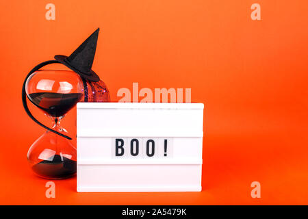 Halloween themed Kino Leuchtkasten auf der hellen orange Hintergrund mit lustigen Hexe Hut und schwarzen sand Sanduhr Stockfoto
