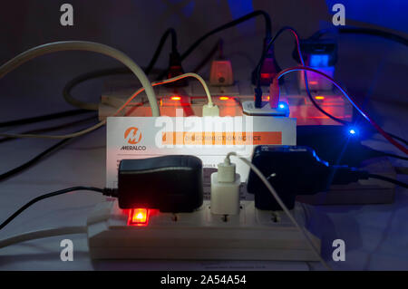 Dramatische Nacht geschossen von mehrere überlastete Platinen Steckschlüsselverlängerung mit MERALCO trennen. Stockfoto