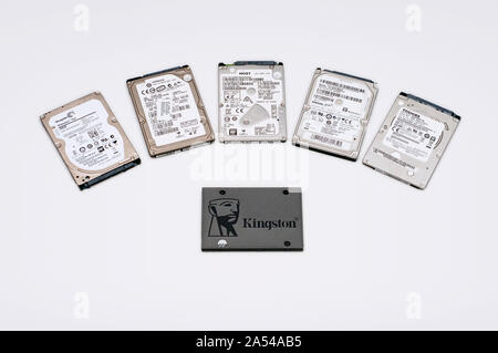 Eine schwarze SSD durch fünf HDD in Weiß isoliert Hintergrund umgeben. Viele langsame Performance Hard Disk und eine super schnelle Leistungssteigerung solides St Stockfoto