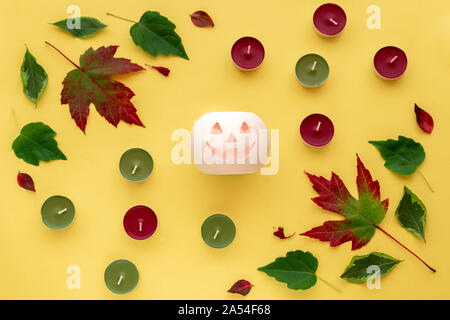 Halloween Komposition. Blätter, Kerzen, Kürbis auf gelben Hintergrund. Herbst, Herbst, halloween Konzept. Herbstferien card Design. Platz kopieren, Ansicht von oben, flach. Stockfoto