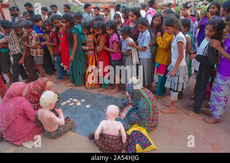 Die Mitglieder des Erweiterten Indischen albino Familie um Spenden in Udipi, Karnataka, Indien, umgeben und starrte durch eine Schar von Einheimischen Stockfoto