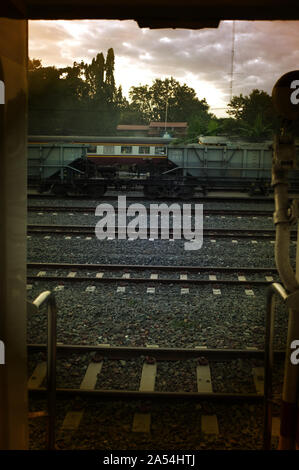 Ein bunter Sonnenaufgang über einem kleinen Bahnhof in Thailand Stockfoto