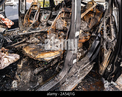 Ein Brandopfer Innenraum nach einem Brand oder einem Unfall auf einem Parkplatz, mit Rost und Steinkohle mit verstreuten Ersatzteile rund um. Raub, Brandstiftung, Stockfoto