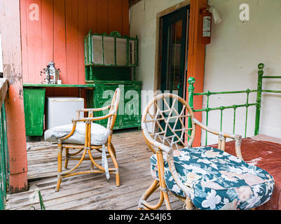 Terrasse eines alten Vintage House mit hölzernen stulphi und grüne und rote Geländer in der Nähe von Retro Bett. Einrichtung und Innenarchitektur. Stockfoto