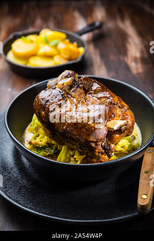 Röster Schweinshaxe mit Wirsing und gebackene Kartoffeln - traditionelle Gerichte der deutschen Küche, Eisbein, Schweinehaxe Stockfoto