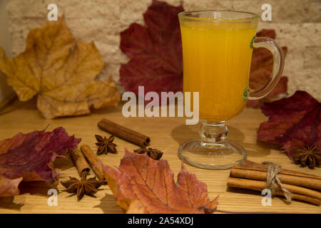 Tee aus Sanddorn Beeren und Gewürzen. Herbst Szene mit Anis Sterne und Zimtstangen, Dekoration von getrockneten bunten Blättern: rot, orange und gelb Stockfoto