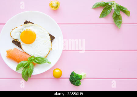 Spiegeleier Toast mit Lachs und Brokkoli auf bunten rosa Tabelle Hintergrund, kopieren. Stockfoto