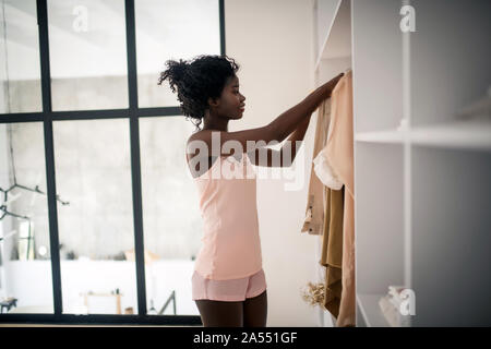 Schlanke Frau mit Schlafanzug in der Nähe von Schrank stehend Stockfoto