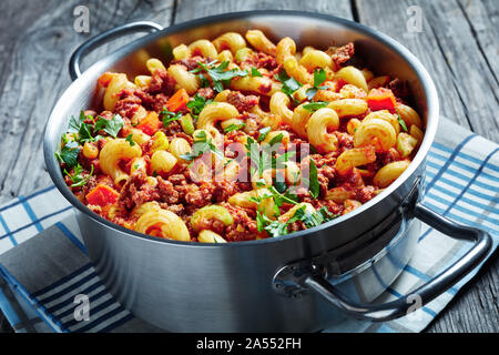 In der Nähe von amerikanischen italienischen Gulasch Ellenbogen Nudeln, Rindfleisch, Sellerie und Tomaten in einer Metall Topf auf einem rustikalen Holztisch mit Serviette, Ansicht von Abo Stockfoto