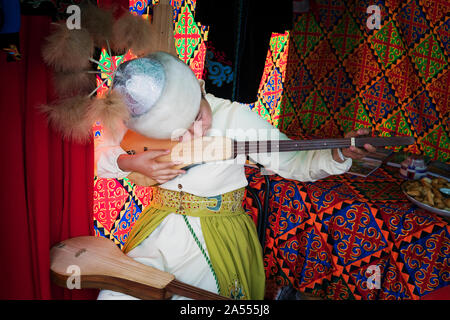 Asiatische Frau in traditioneller Kleidung spielt eine gezupfte Musikinstrument. Festival der traditionellen Kulturen im Altai. Barnaul. 7. September 2019 Stockfoto