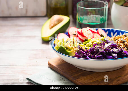 Buddha Schüssel mit Regenbogenfarben Zutaten - Avocado, fermentiert, Rotkohl, Quinoa, Rettich, grüne Bohnen, Sesam und Kürbiskernen. Teller serviert auf nicht Stockfoto