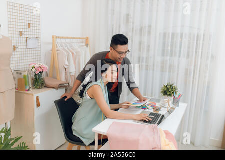 Junge weibliche und männliche Fashion Designer Team sprechen über neue Kollektion, diskutieren Stoffe und Muster für die neue Kollektion in Schneiderin s studio o Stockfoto