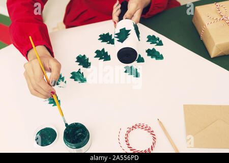 Frau Malerei auf ihre chirstmas Baum Papier. Xmas-Konzept Stockfoto