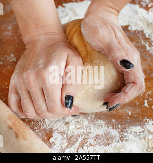 Die Frau Hände kneten den Teig auf einem Holztisch Nahaufnahme Stockfoto