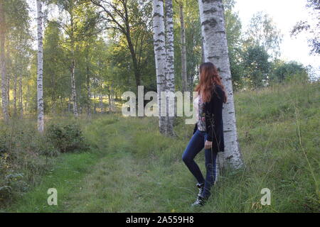 Frau lehnte sich an einen Baum im Frühling. Stockfoto