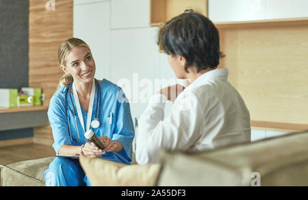 Schöne lächelnde Frau der Arzt in einer Flasche Pille bietet den Patienten Stockfoto