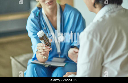 Schöne lächelnde Frau der Arzt in einer Flasche Pille bietet den Patienten Stockfoto