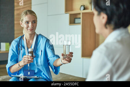 Schöne lächelnde Frau der Arzt in einer Flasche Pille bietet den Patienten Stockfoto