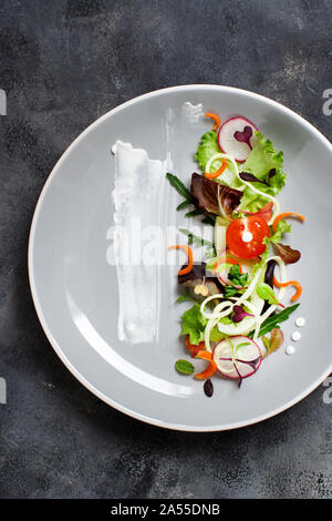 Grüner Salat mit microgreens auf einer schwarzen Platte Top View Stockfoto