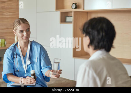 Schöne lächelnde Frau der Arzt in einer Flasche Pille bietet den Patienten Stockfoto