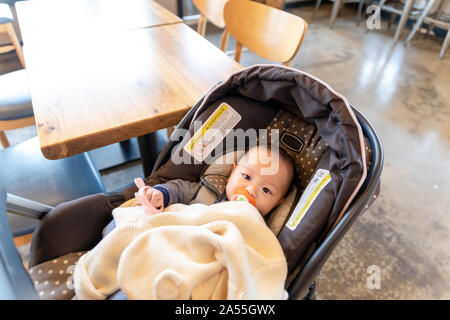 Cute asian Baby mit Schnuller im Kind Kinderwagen. Baby Blick in die Kamera. Stockfoto