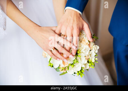 Eine neu weding Paar legen sie ihre Hände auf einer Hochzeit Bouquet zeigen Ihre Trauringe. Stockfoto