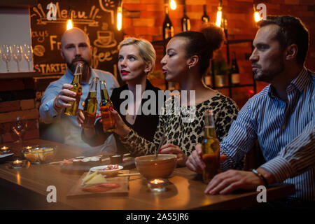 Gruppe von Freunden Fernsehen in einem Cafe hinter dem Tresen. Stockfoto