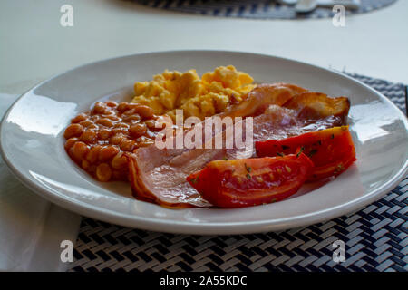 Englisches Frühstück mit gegrilltem Speck, Tomaten, Rührei und gebackene Bohnen in Tomatensoße in Spanien Stockfoto