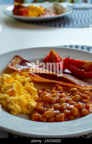 Englisches Frühstück mit gegrilltem Speck, Tomaten, Rührei und gebackene Bohnen in Tomatensoße in Spanien Stockfoto