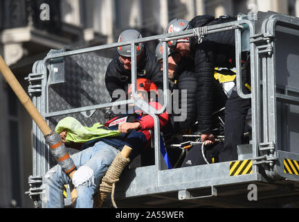 Polizei versucht eine Demonstrantin, die saß auf einem Bambus Struktur der Straße am Oxford Circus, London, während einer Aussterben Rebellion (XR) Klimawandel protest Block ist zu entfernen. Stockfoto