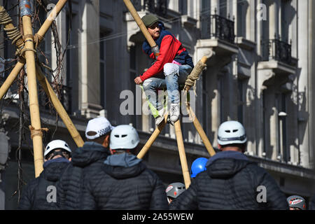 Polizei versucht eine Demonstrantin, die saß auf einem Bambus Struktur der Straße am Oxford Circus, London, während einer Aussterben Rebellion (XR) Klimawandel protest Block ist zu entfernen. Stockfoto