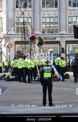 London, Großbritannien. Okt, 2019 18. Klima Demonstranten sitzen in einem hölzernen Struktur von der Polizei in Oxford Circus umgeben. Credit: Kevin Shalvey/Alamy leben Nachrichten Stockfoto