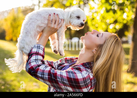 Schöne Frau verbringt Zeit mit ihrem Malteser Hund outdoor. Stockfoto