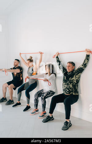 Freunde Hocken gegen die Wand mit Widerstand Band Stockfoto