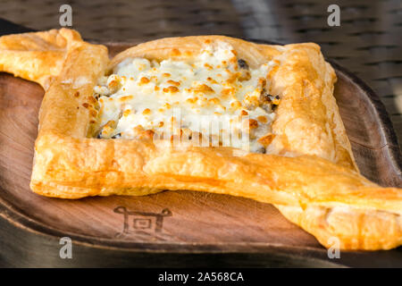 Khachapuri Blätterteig mit Huhn und Pilzen auf einem Holzbrett. Close-up essen Hintergrund. Georgische Küche Konzept. Georgische Käse Brot Stockfoto