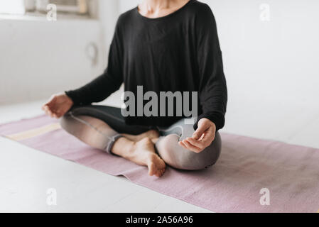 Frau sitzt im Lotussitz in Yoga Studio Stockfoto