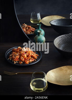 Rustikale Low Key noch Leben mit Platte von Chili pflaume Fried Chicken und gemischte Nüsse auf dem Tisch Stockfoto