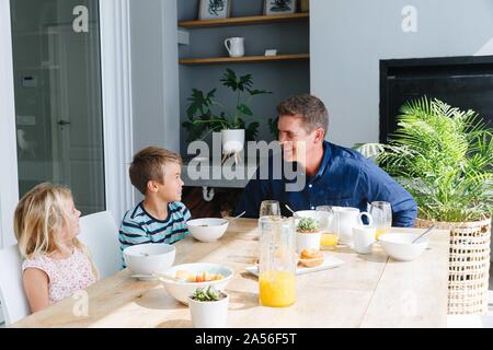 Vater sprechen mit Kindern beim Mittagessen zu Hause Stockfoto