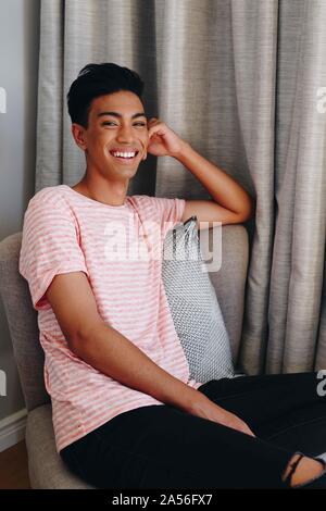 Glückliche junge Mann sitzt auf Schlafzimmer Stuhl, Porträt Stockfoto