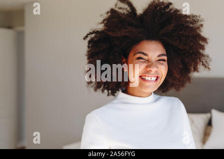 Junge Frau mit Afro Frisur im Schlafzimmer, Kopf und Schulter portrait Lachen Stockfoto