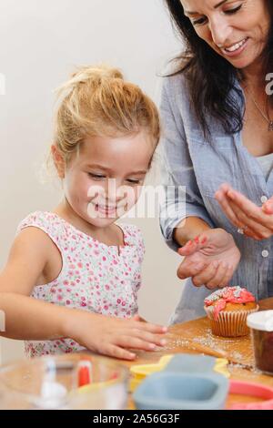 Mutter und Tochter dekorieren Cupcake mit Zuckerguss in der Küche Stockfoto