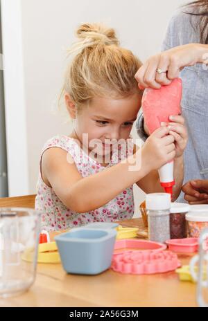 Mutter und Tochter dekorieren Cupcake mit Zuckerguss in der Küche Stockfoto
