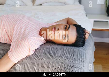 Junger Mann Rücken liegend auf dem Bett, Porträt Stockfoto