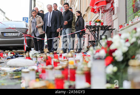 18. Oktober 2019, Sachsen-Anhalt, Halle: Reiner Haseloff (4. von links, CDU), Ministerpräsident von Sachsen-Anhalt, und Izzet Cagac (3. von rechts), Betreiber des Kiez Döner Kebab, stehen vor der Blumen und Kerzen vor dem Laden. Haseloff und Beauftragter der Bundesregierung für die Opfer haben die Kiez-Döner, die von den Rechten Terroranschlag betroffenen besucht wurde. Beide haben die Eigentümer der Snackbar und seinen Mitarbeitern für ihre Unterstützung zugesichert. Am 9. Oktober die Deutsche Stephan B., schwer bewaffnet, hatte zunächst versucht, eine Synagoge zu durchdringen. Wenn sein Plan scheiterte, schoß er 40 Jahr Stockfoto